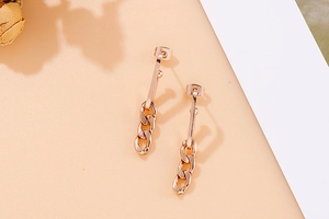 Macro shot of rose gold titanium steel chain earrings on a minimalist decorative background