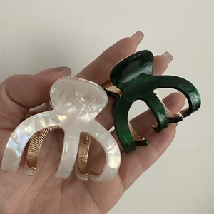 Detail of marble pattern acetate hair claws in pearl white and dark emerald green