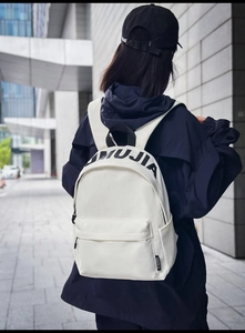 White casual nylon backpack for students shown from behind in a city setting
