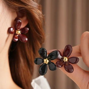 Close-up of vintage flower earrings in deep red and black with golden stamen detail