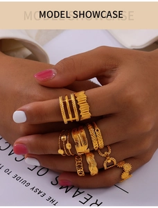 Nahaufnahme von goldenen geometrischen Ringen und Federdesign an einer Modellhand