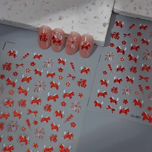 Macro shot of festive red and gold New Year nail art stickers with traditional motifs