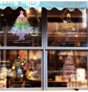 Detailed view of four artistic hand-drawn Christmas tree window stickers with Merry Christmas text