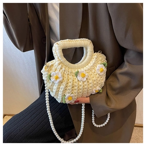 Detail of a handmade cream crochet shell bag with daisy patterns and pearl strap