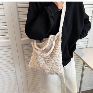 Detail view of cream white knitted shoulder bag with diamond texture on model