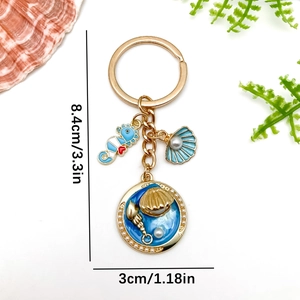 Golden keychain featuring blue seahorse and shell pendants with pearl ocean element