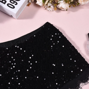Détail d'un short noir à paillettes avec bordure en dentelle sur fond rose texturé