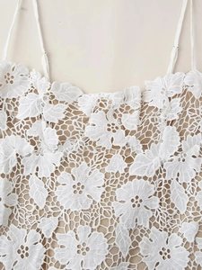 Gros plan des détails de dentelle florale et des fines bretelles de la robe blanche