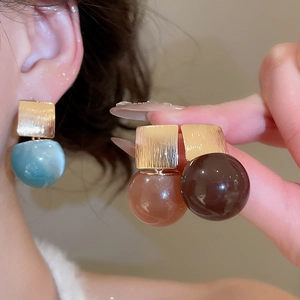 Detail of geometric resin earrings with brushed gold metal square and colorful sphere