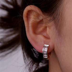 Close-up of gold U-shaped hoop earring with inset sparkling white zircons on ear