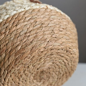 Bottom view of a woven plant basket showing natural straw fibers and intricate textures