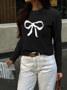 Detail of black knit sweater featuring a white bow pattern print for a casual vacation look