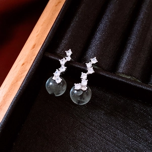 Close-up of zircon drop earrings with glass orb pendants in a black velvet jewelry box