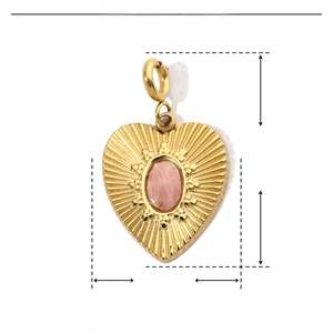 Macro detail of a 24mm gold heart pendant with pink natural stone and radial texture