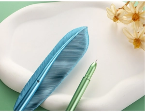 Detail of creative blue metal feather pen with intricate texture on an elegant tray