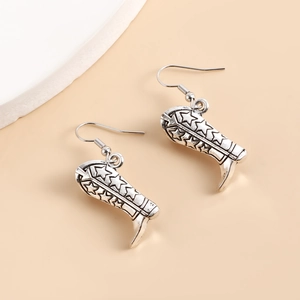 Gros plan détaillé sur des boucles d'oreilles bottes de cowboy vintage en argent punk