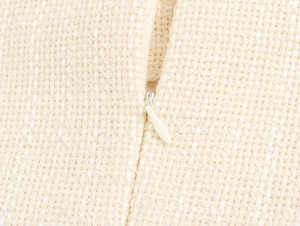 Dettaglio macro del tessuto in tweed beige di qualità e chiusura a zip invisibile bianca