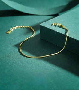 Detailed view of gold 925 sterling silver snake chain bracelet with lobster clasp and tag