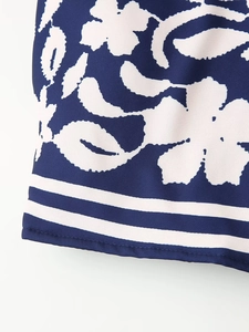 Dettaglio del tessuto blu navy con motivi stampati bianchi e bordo a righe sul cappotto