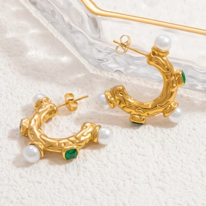 Detailed view of 18k gold earrings with white pearls and square green emerald gemstone