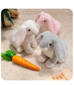 Close-up of soft plush bunny toys in white pink and blue with realistic carrot props