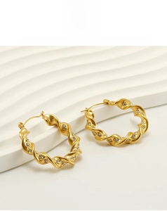 Close-up of twisted rope hoop earrings in 18k gold plating with white crystals