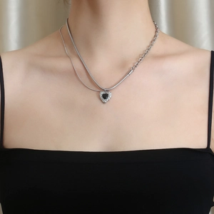 Close-up of double layer silver chain with black heart pendant on female model