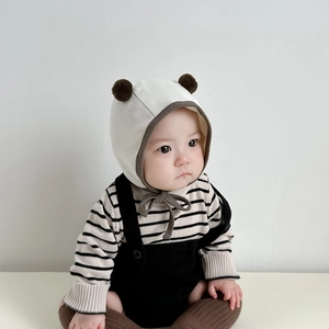 Detail of infant knit earflap hat with cute plush pom-poms and secure chin ties