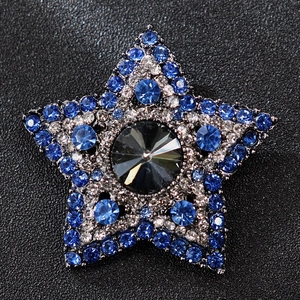 Macro shot of luxury star brooch with blue rhinestones and gray faceted gemstone