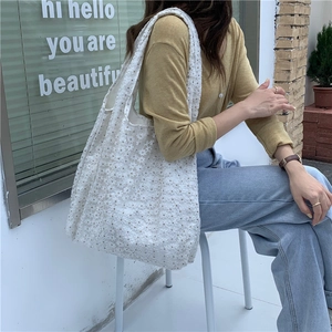 Detail of white floral lace tote bag showing intricate crochet patterns and shoulder strap