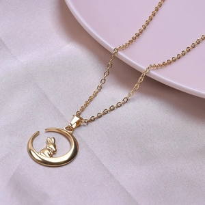 Detail shot of a 18k gold plated moon and rabbit pendant on a silky pink fabric