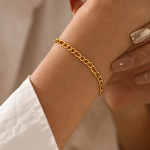 Elegant gold plated stainless steel Figaro chain bracelet for women on a model's wrist