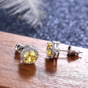 Macro shot of silver halo stud earrings with round yellow gemstone and pavé diamonds