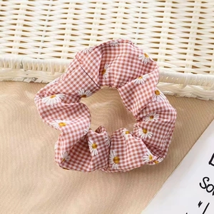 Detail of floral scrunchie featuring orange gingham fabric and white daisy embroidery