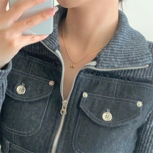 Detailed view of the gold starburst pendant necklace worn over a blue denim jacket