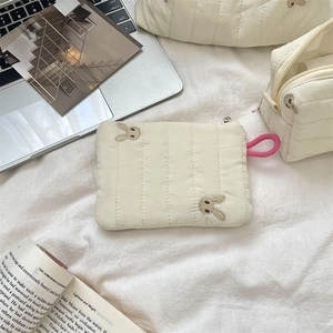 Detailed close-up of quilted storage bag featuring rabbit embroidery and pink strap loop