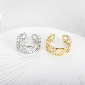 Close-up of gold and silver open rings with hollow heart pattern on white display tray