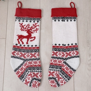 Detail of knitted Christmas stockings with reindeer pattern on light wood floor