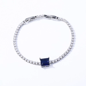 Detail of silver-tone tennis bracelet with clear zircons and a deep blue square main stone