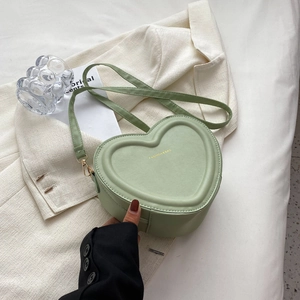 Dettaglio della borsa a tracolla a cuore verde chiaro con finiture dorate su tessuto