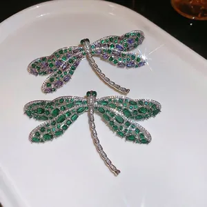 Elegante libellenbroche set met smaragd en amethist edelstenen op keramische plaat