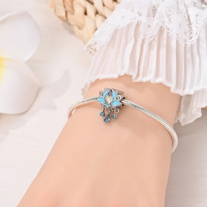 Detailed view of a silver lotus charm bracelet with blue gemstones on a model's wrist