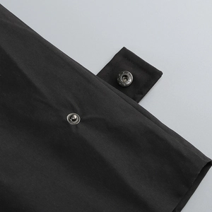 Détail de la robe blazer noire montrant la texture du tissu et le bouton pression en métal
