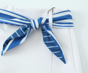 Detail of white striped pants with a blue and white striped bow belt and hidden zipper