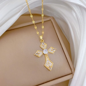 Macro shot of gold-plated cross pendant encrusted with clear crystals on white silk