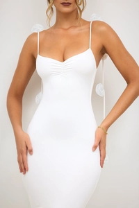 Détail de la robe blanche moulante avec fleurs 3D sur les bretelles et buste froncé