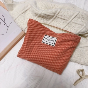 Detail of orange houndstooth cotton makeup bag with Time to Party label on knit fabric