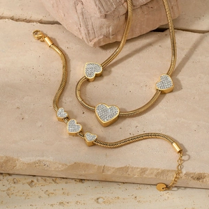 Elegant gold heart jewelry set featuring necklace and bracelet on stone background