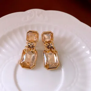 Elegant gold vintage earrings with champagne gems and floral relief on a ceramic plate