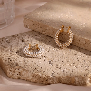 Macro detail of 18K gold plated hoop earrings with micro-set pearls on natural stone